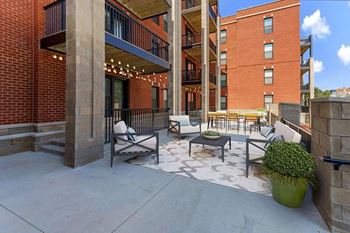 A patio with a table and chairs is surrounded by brick buildings at Circ Apartments, Richmond, Virginia